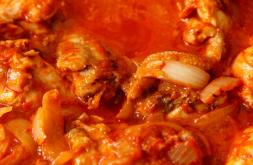 A pot of red sauce with chicken in it