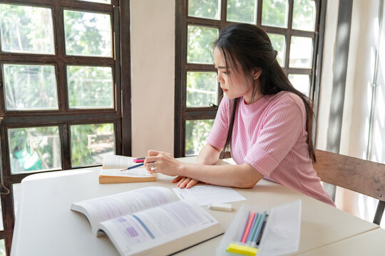 Asian girl student doing exam hand holding pencil writing answer in university classroom education high school or university student taking notes while preparing for exam