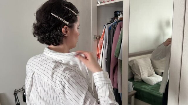 The woman gets dressed and buttons up her shirt.
