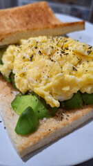 Egg and avocado toast served on a white plate