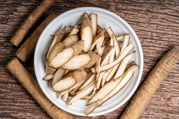 Slide Gobo Root or Burdock Root an Asian culinary herb on white plate, Burdock root for Japanese cooking isolate on wooden background.