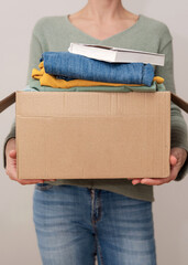 Vertical close up of a woman holding cardboard box with used clothes and items for charity and...