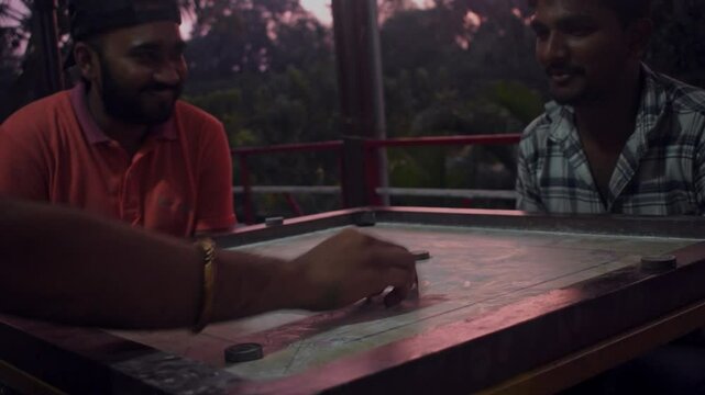 Dandeli, Karnataka- 6th december 2024:A group of friends enjoying a game of carrom indoors, with an evening view in the background.