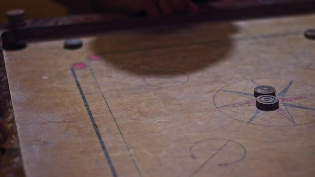 A group of friends enjoying a game of carrom indoors.
