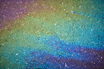 Colorful oil spill creating rainbow patterns on asphalt