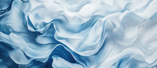 Obraz premium Soft flowing fabric in shades of blue and white, smooth textures creating layered waves, ideal for backgrounds or elegant design themes.