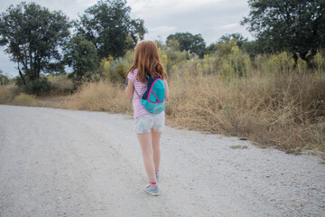  girl, hiking field with backpack. child backpacker walking in nature. Summer. Horizontal
