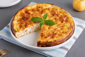 A delicious homemade cottage cheese casserole served on a textured table with fresh mint under bright kitchen lighting.
