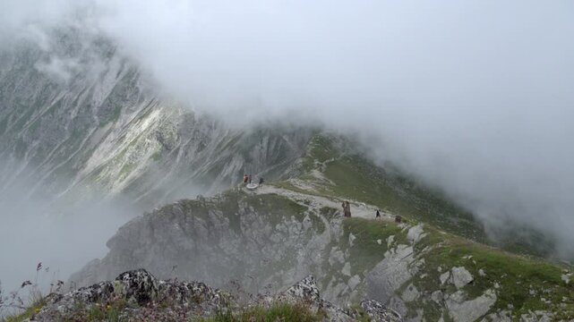 Clouds moving in on hikers just below the summit of Mount Ifinger, Sarntal Alps, South Tyrol, Italy
