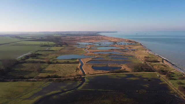 Aerial view of the wetlands along the Normandy coast in France, revealing a striking contrast between natural beauty and historical significanc