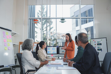 Businesswoman presenting growth data on computer screens to colleagues during a meeting in a modern...