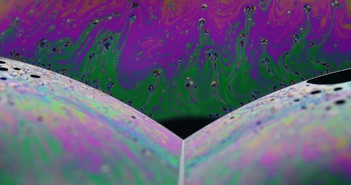 Oilslick colors and complex movements showing on the surface of 3 intersectiong soap bubbles