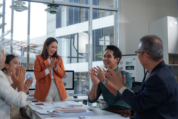 Happy diverse colleagues clapping hands and celebrating successful teamwork during a meeting in a...