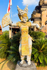 A Balinese Legong dancer statue in gold attire with intricate carvings. Holding an ornamental fan, the figure gracefully poses, symbolizing elegance and cultural heritage.
