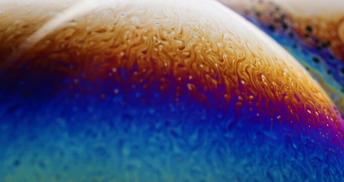 Slow zoom in on soap bubbles, as small gust of wind shakes them around and mezmerizing patterns on the surface swirl across the vapor looking film