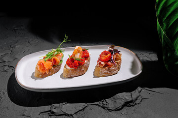 Three gourmet tapas served on rustic bread with vibrant toppings in a stylish setting