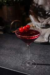 Elegant cocktail with cherry garnish served in a stylish glass on a dark countertop at a bar in the evening