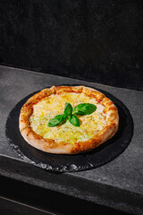 Freshly baked pizza topped with basil on a dark stone surface in a modern restaurant setting