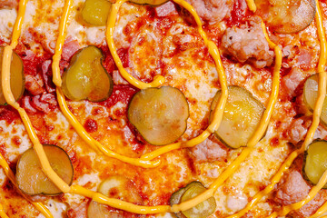 Delicious pizza topped with pickles, cheese sauce, and sausage served on a golden crust in a warm setting