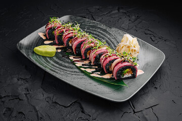 Delicious sushi roll presented elegantly on a dark plate with wasabi and pickled ginger