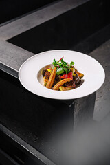 Gourmet dish featuring grilled vegetables and a savory meat preparation served in a modern dining setting