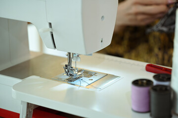 Close up of a sewing machine with thread and fabric at fashion designer workspace