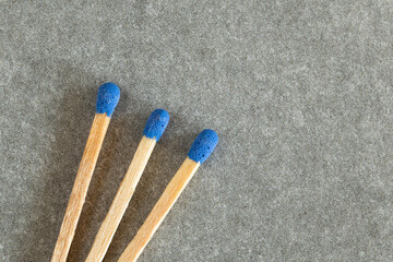 three blue-tipped matches on textured surface