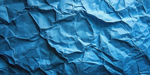 Fototapeta premium Crumpled texture of deep blue paper background with intricate folds and shadows providing ample copy space for design applications