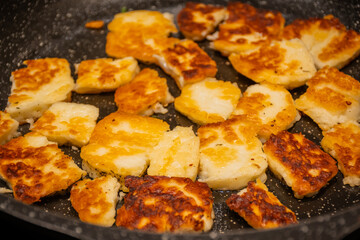 fried Mediterranean Greek Cyprus haloumi sheep or goat cheese in frying pan skillet on home kitchen stove. delicious comfort food unhealthy but tasty