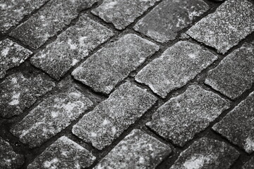 A classic black and white image of an old brick road with a worn surface.