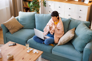 Woman having online doctor's exam using laptop computer while sick at home
