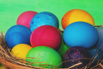 Colorful easter eggs in a basket on a wooden table