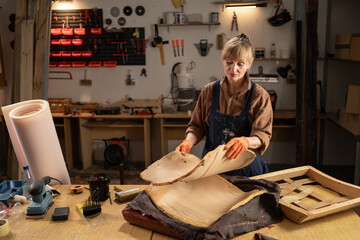 Woman restorer restoring old chair or armchair preparing new upholstery for antique furniture