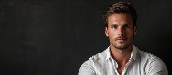 Obraz premium Young man with stylish haircut wearing a white shirt against dark background showcasing Copy Space for text placement.