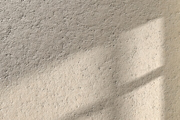 A concrete textured wall with natural shadows from
sunlight coming through a window that can be used in various designs.
