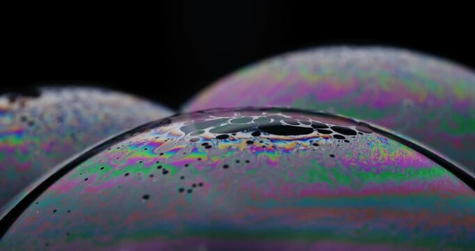 Macro zoom to top part of soap bubble as dark spots of thin soap film gather there, causing bubble to burst