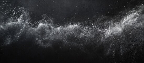Abstract dark background with dynamic white splashes resembling chalk dust creating a dramatic chalkboard effect for artistic projects.