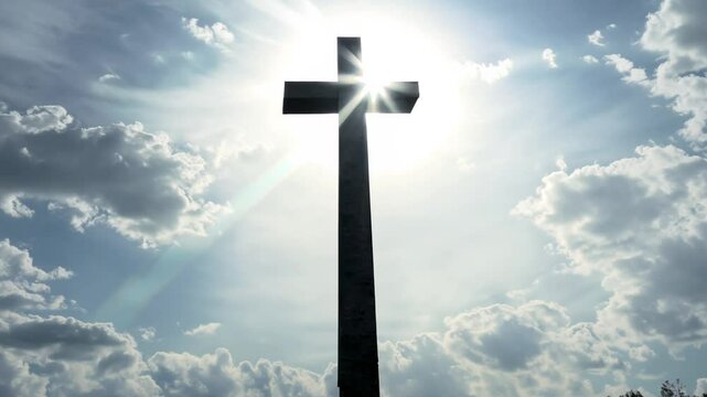 Backlit silhouette video, tilt down from a bright, cloudy sky to reveal a church cross, sunlight breaking through, suggesting divine intervention