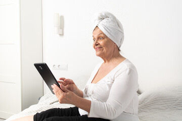Caucasian senior woman with wrinkles talking with somebody by tablet