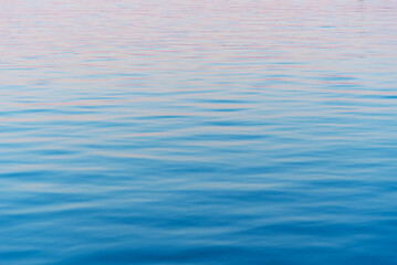 Calm water surface with gentle ripples reflecting soft sunset hues