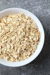 Composition with oatmeal flakes on gray background. Cooking breakfast