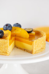Homemade cut mango panna cotta tart on a stand. Sugar, sugar substitutes, lactose and gluten free. Vegan dessert. Vertical orientation.