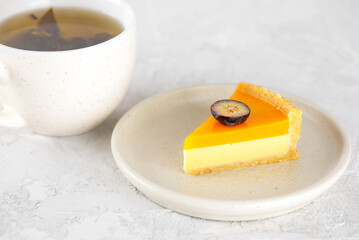Piece of vegan mango tart with fresh blueberry in a plate and cup of tea. Sugar, sugar substitutes, lactose and gluten free.