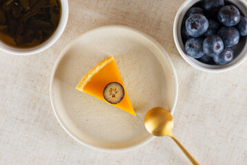 Piece of vegan mango tart with fresh blueberry, mousse from coconut cream in a plate and cup of tea. Sugar, sugar substitutes, lactose and gluten free. Top view.