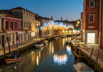 Murano canal with festive star-shaped lights illuminating the evening sky