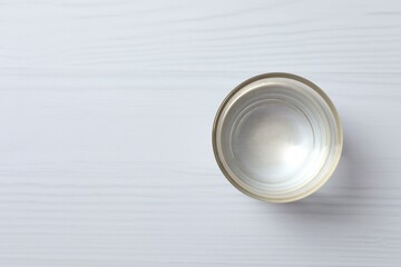 Glass with clear water on white table, space for text