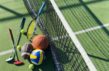 A variety of sports equipment including an american football, a soccer ball, a tennis racket, a tennis ball, and a basketball