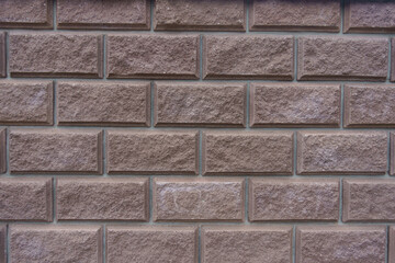 Surface of brownish pink split face brickwork with stretcher bond pattern