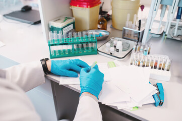 laboratory assistant hands only in disposable sterile gloves makes analyses using pipettes,...