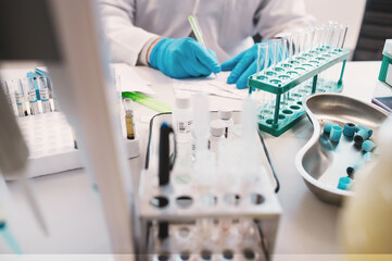 laboratory assistant hands only in disposable sterile gloves makes analyses using pipettes,...